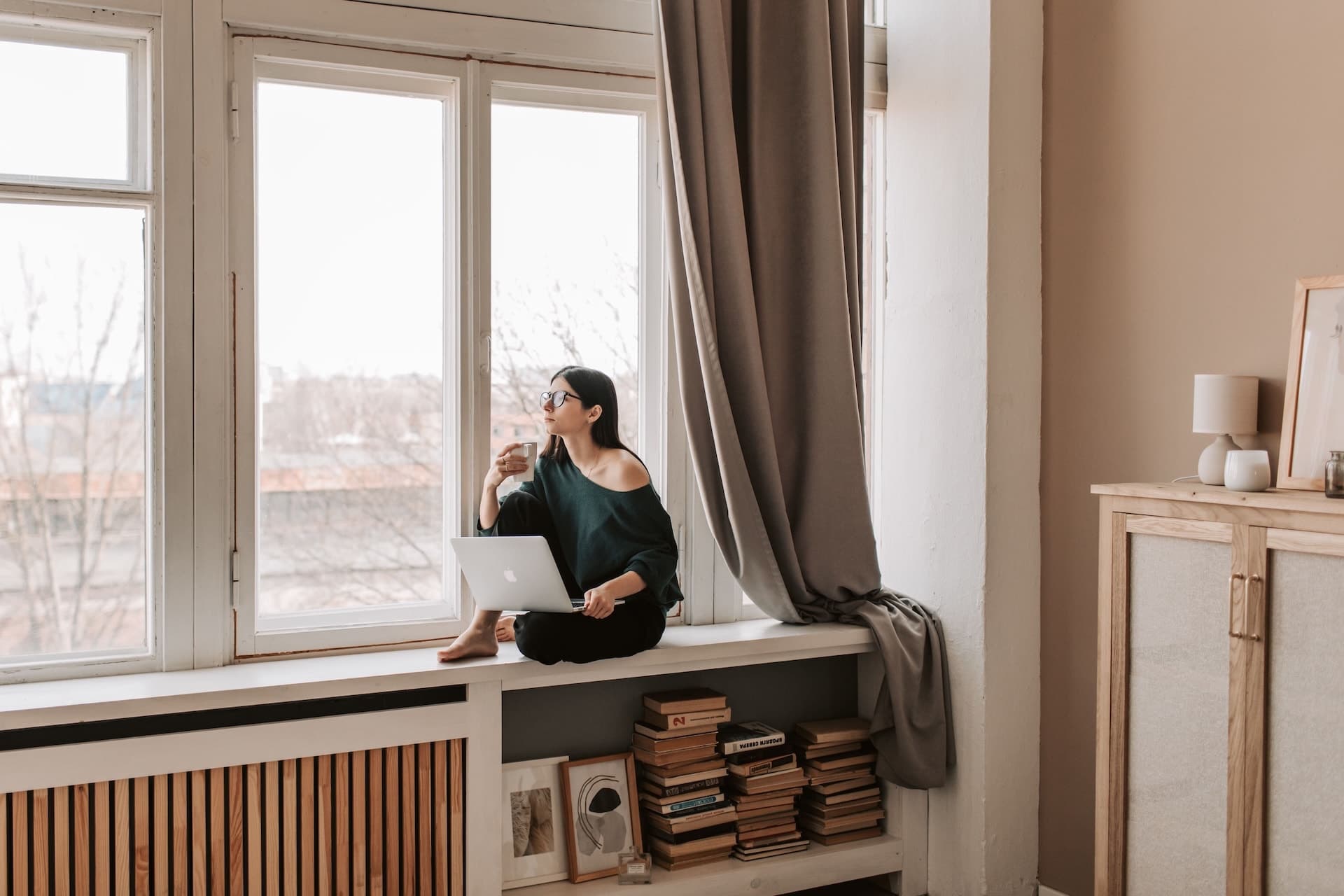 Erwachsene Person schaut in einer ruhigen Umgebung nachdenklich aus dem Fenster